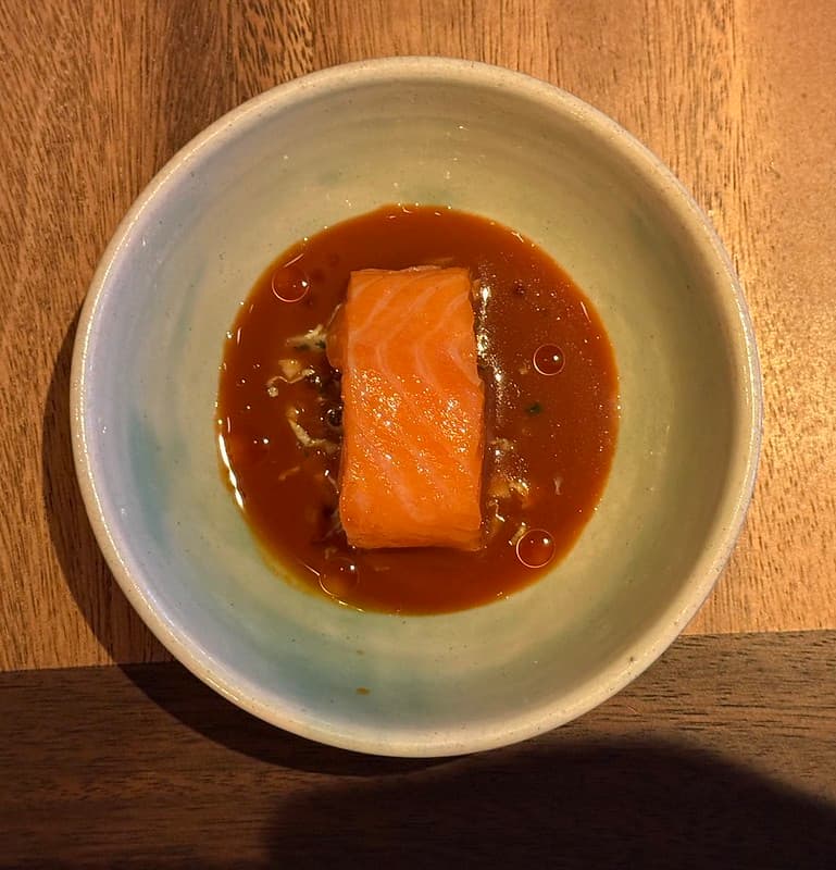 Chalk stream trout in a bluish bowl surrounded by a red/brown curry