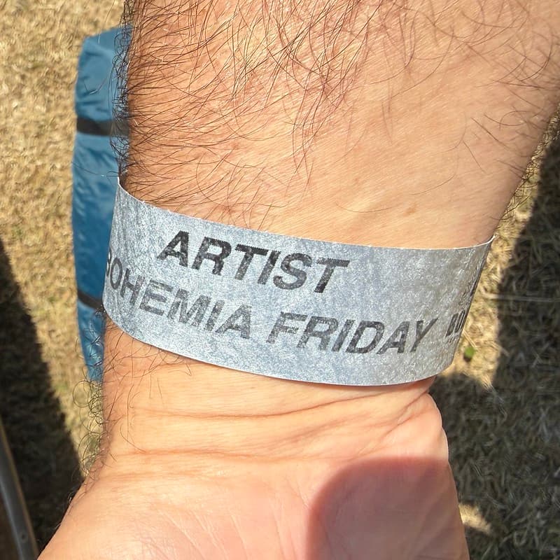 A silver Wristband, around my wrist, that reads Artist Bohemia Friday