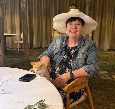 A kitten on Susan's lap investigating her phone