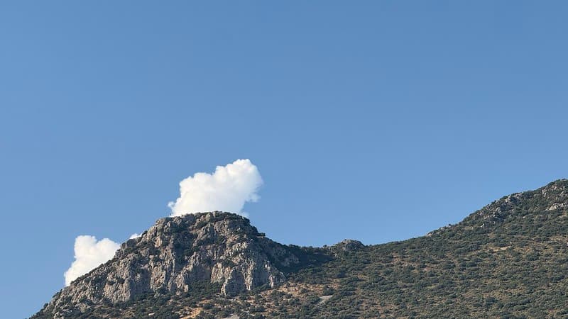 A hill with a cloud, it looks like an erupting volcano